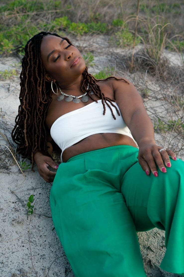 Black women lying on the sandy beach eyes closed wearing green simplicity 9235
