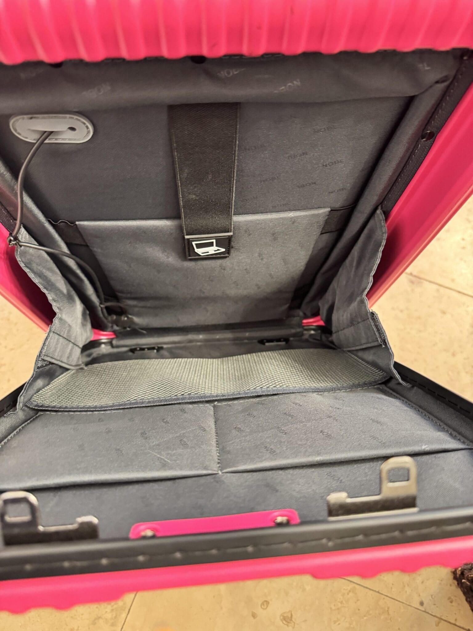 Traveling at the airport with a pink NOBL suitcase and a Tumi backpack