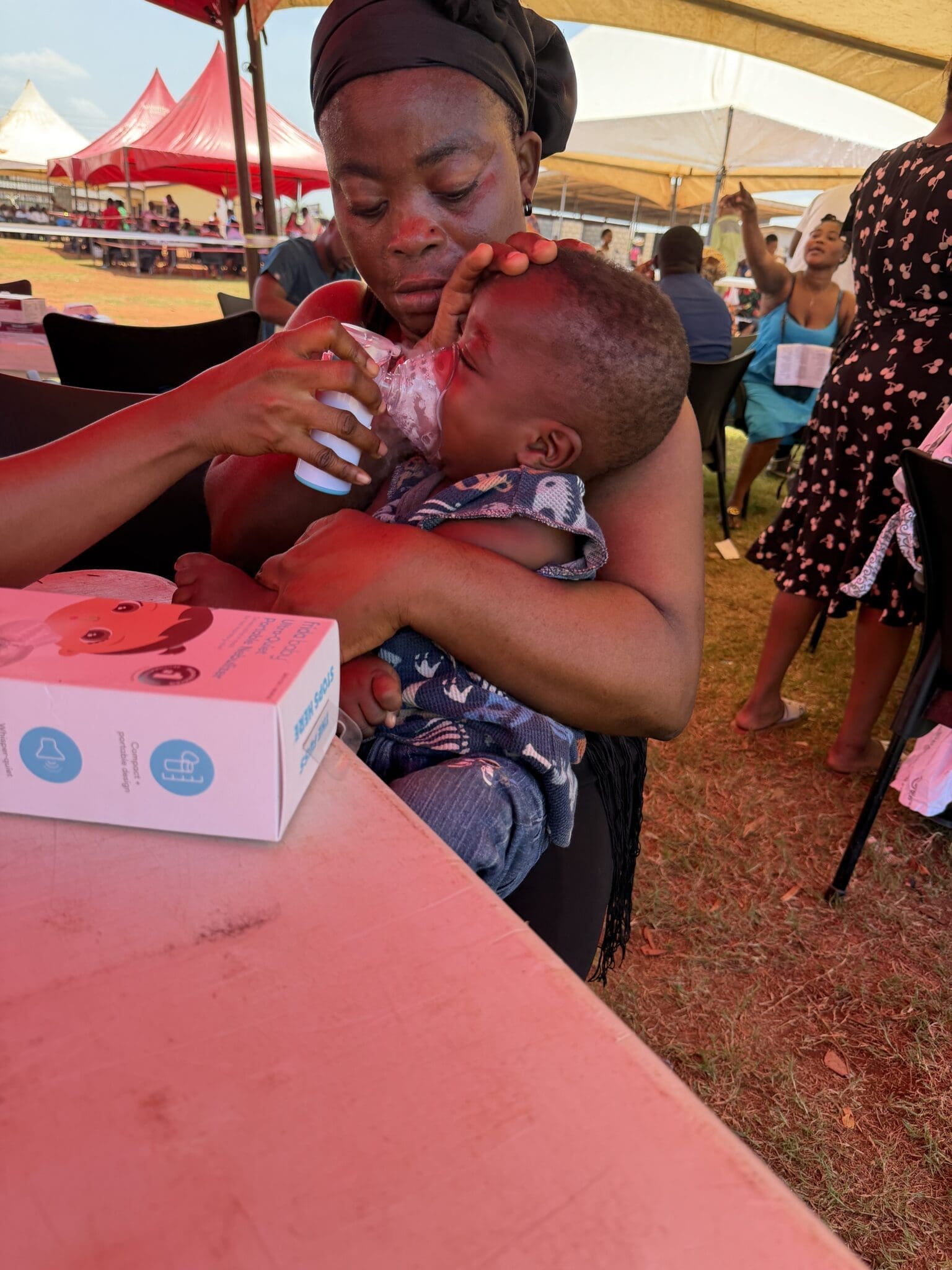 Administering a breathing treatment to a baby in the field in Ghana
